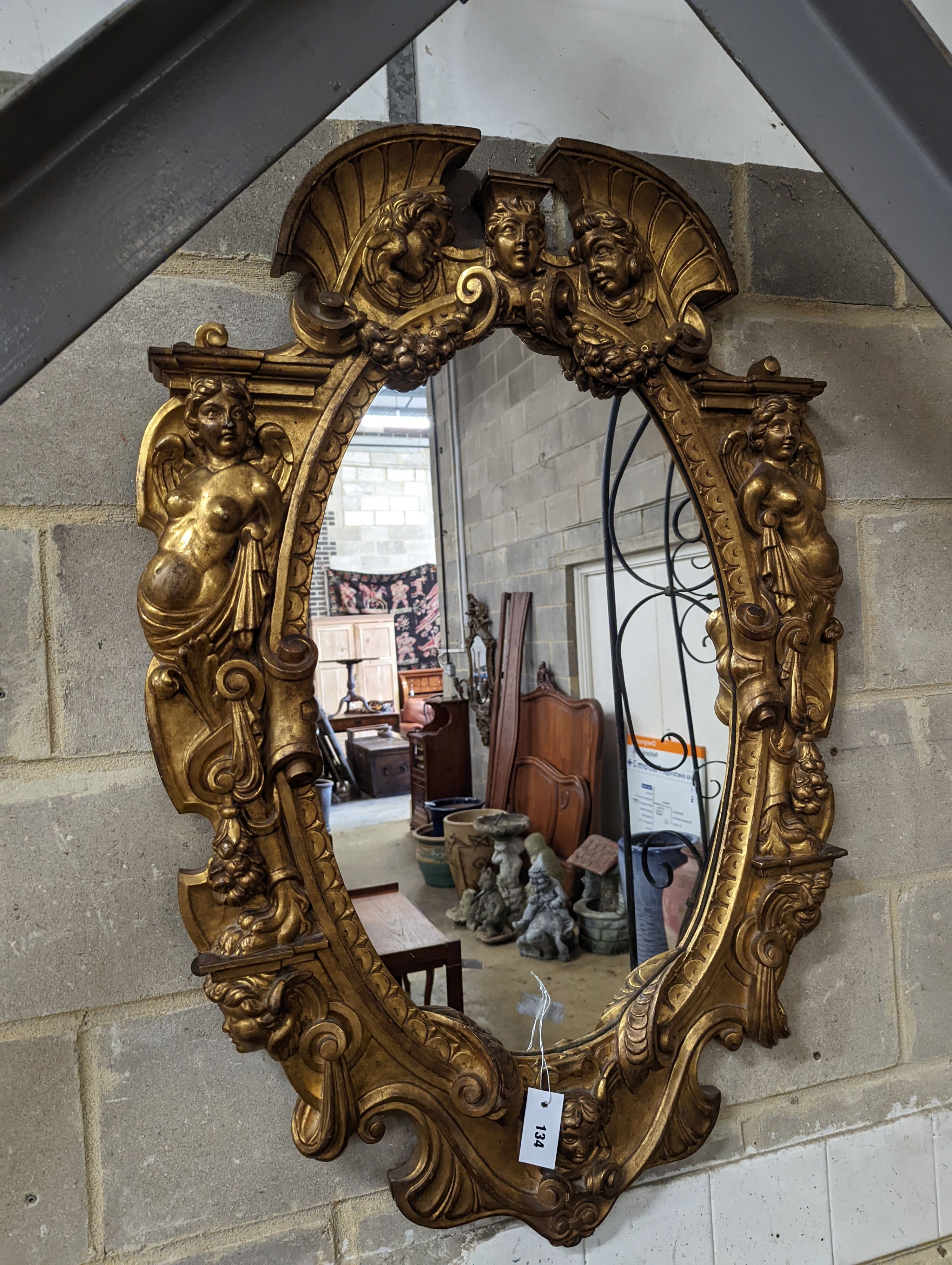A Victorian carved giltwood oval wall mirror decorated with cherubs and C scrolls., width 74cm, height 110cm